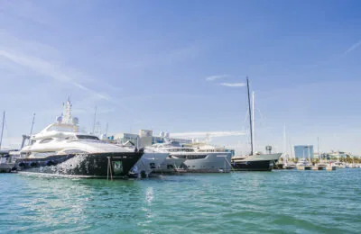 Several luxury yachts are moored in a marina on a sunny day.