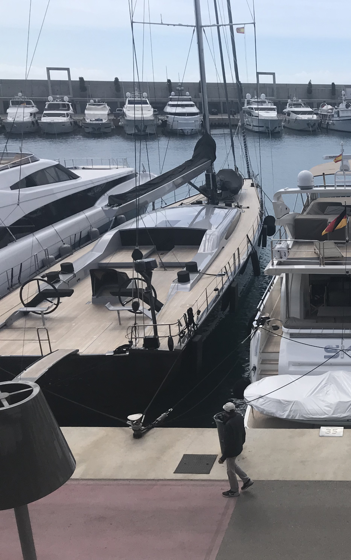 A modern sailing yacht named #36(2) is docked in a marina alongside several other luxury boats.