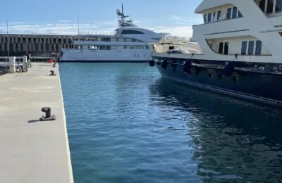 Two luxury yachts docked in a calm marina on a sunny day.