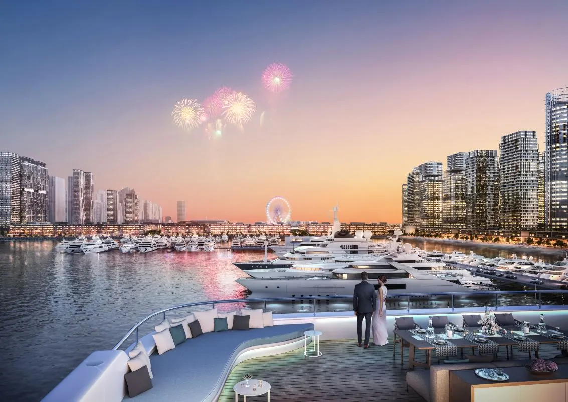Couple enjoying a waterfront view of luxury yachts, modern skyscrapers, and fireworks at sunset from a stylish yacht deck.