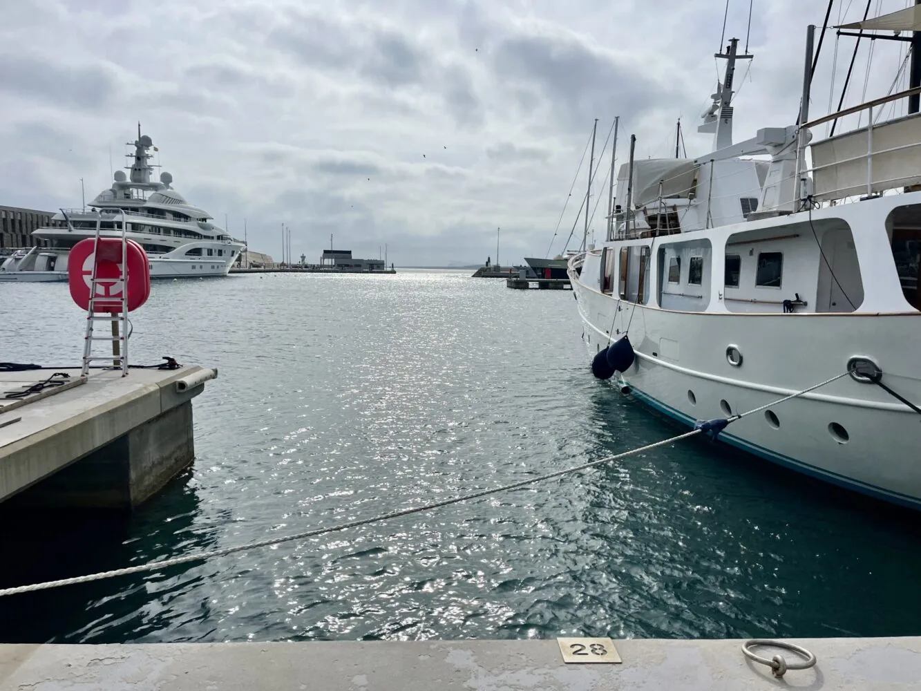 Vista de yates de lujo atracados en una marina, con una plataforma de cemento numerada como parte de la infraestructura portuaria, bajo un cielo nublado.