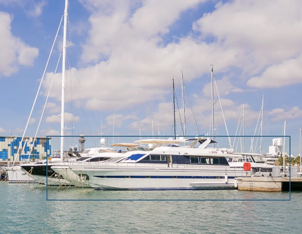A luxury yacht docked at a marina with a partially cloudy sky in the background.