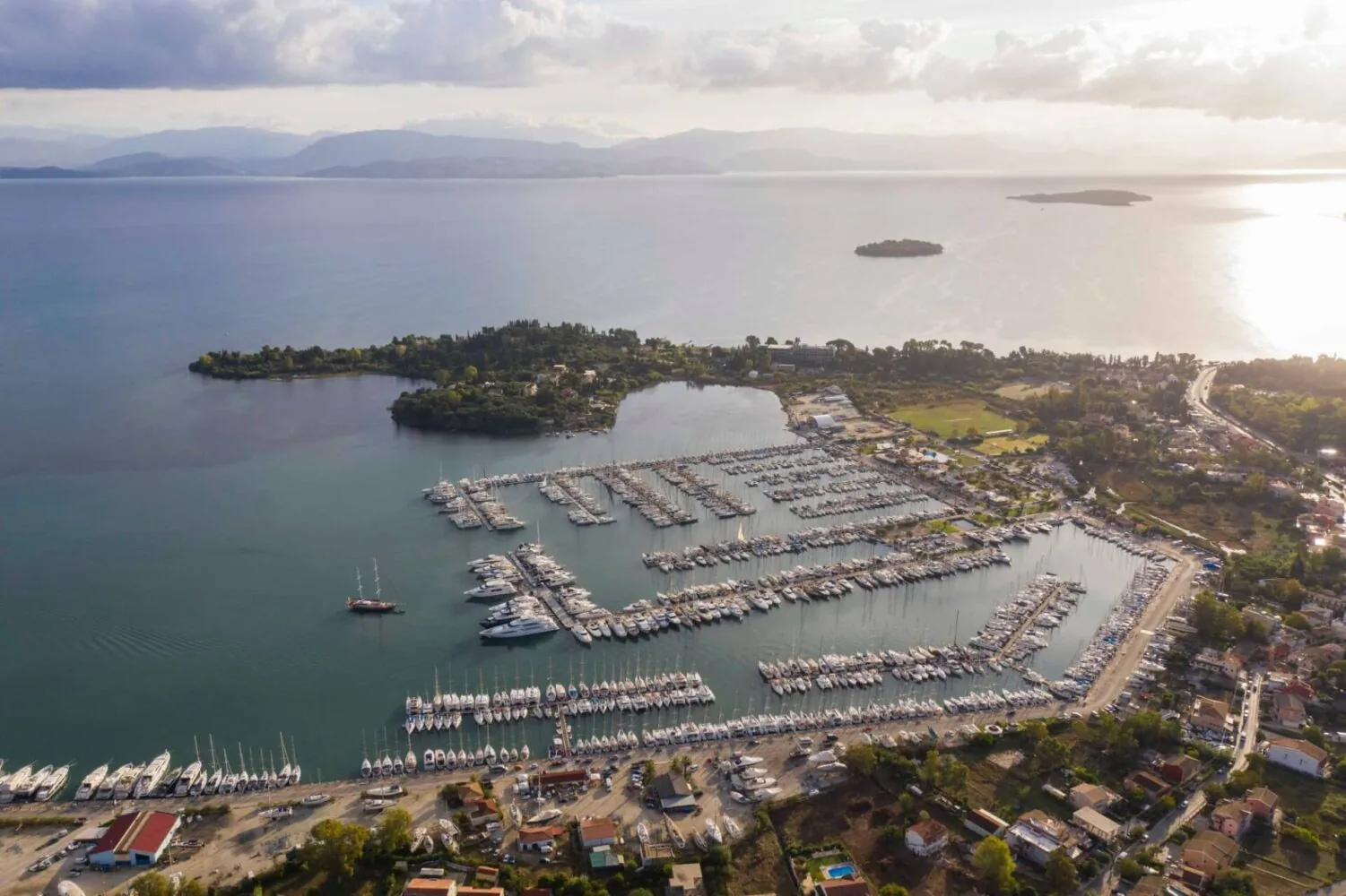 Aerial view of the Gouvia Marina on Corfu Island, Greece, with numerous docked boats and surrounding greenery.