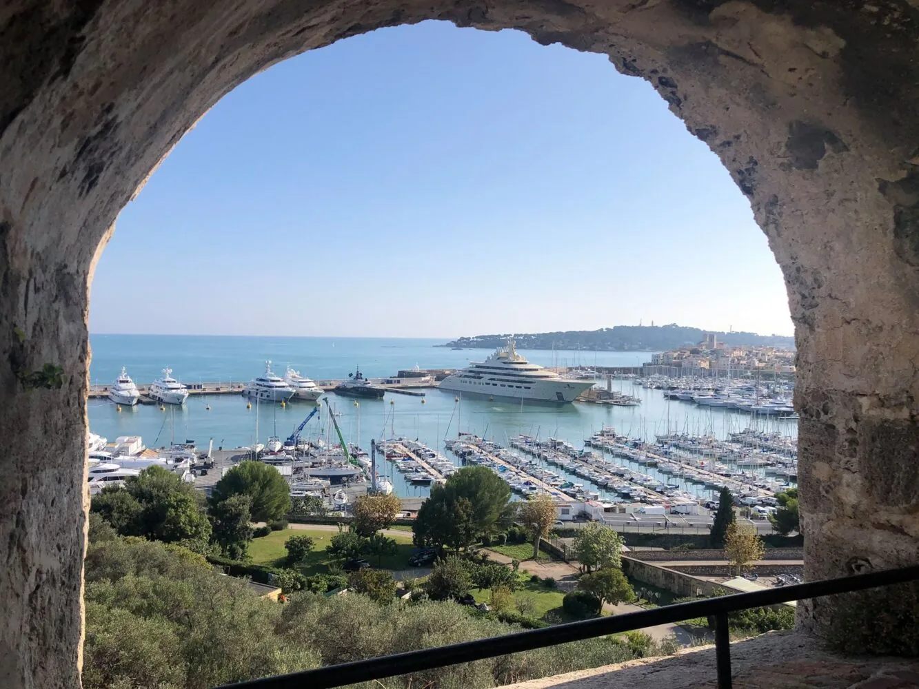 Blick auf Port Vauban durch einen steinernen Torbogen mit zahlreichen Yachten und Booten, die im Yachthafen liegen.