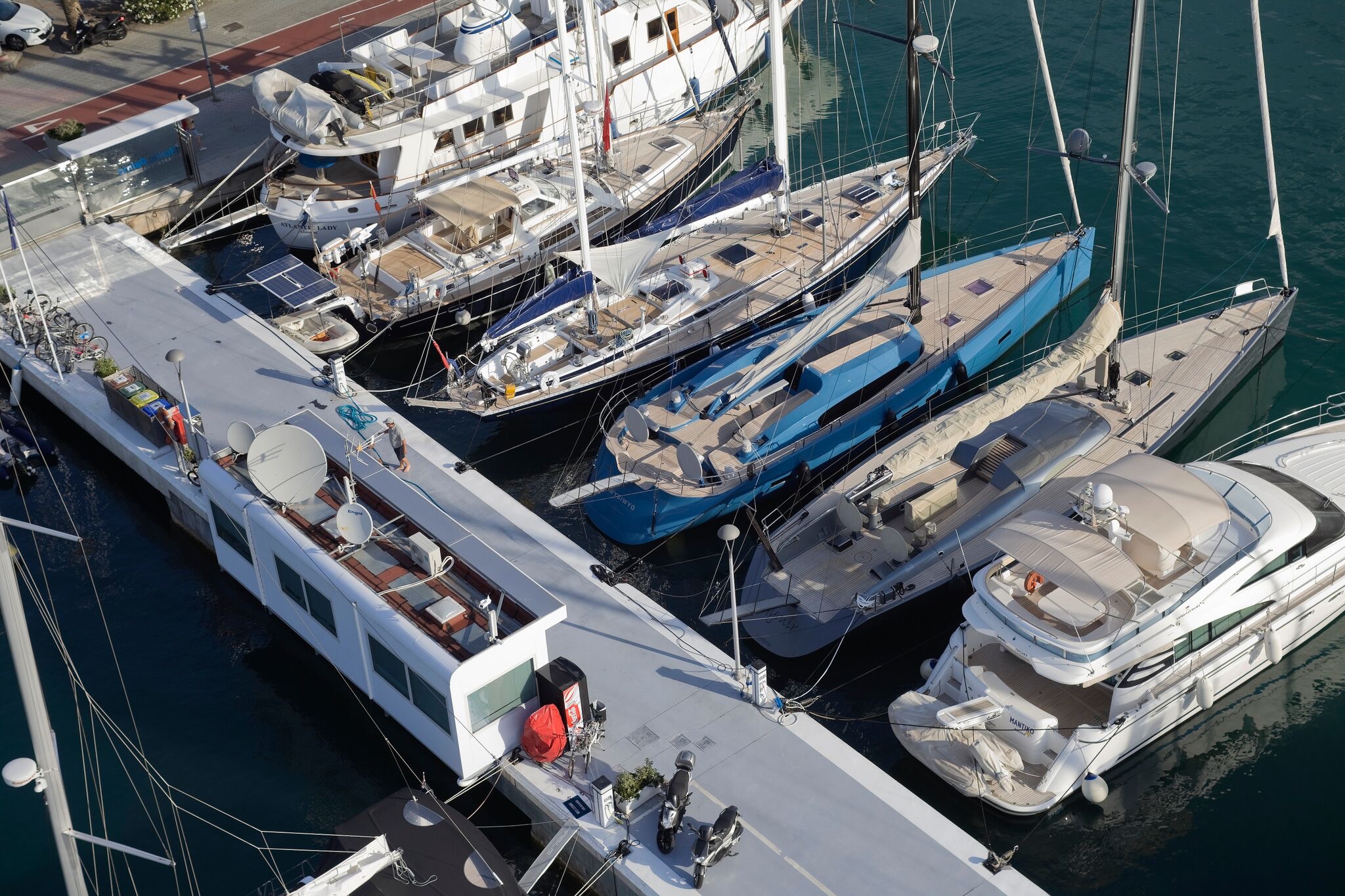 Several luxury yachts are docked side by side at a marina, viewed from above.