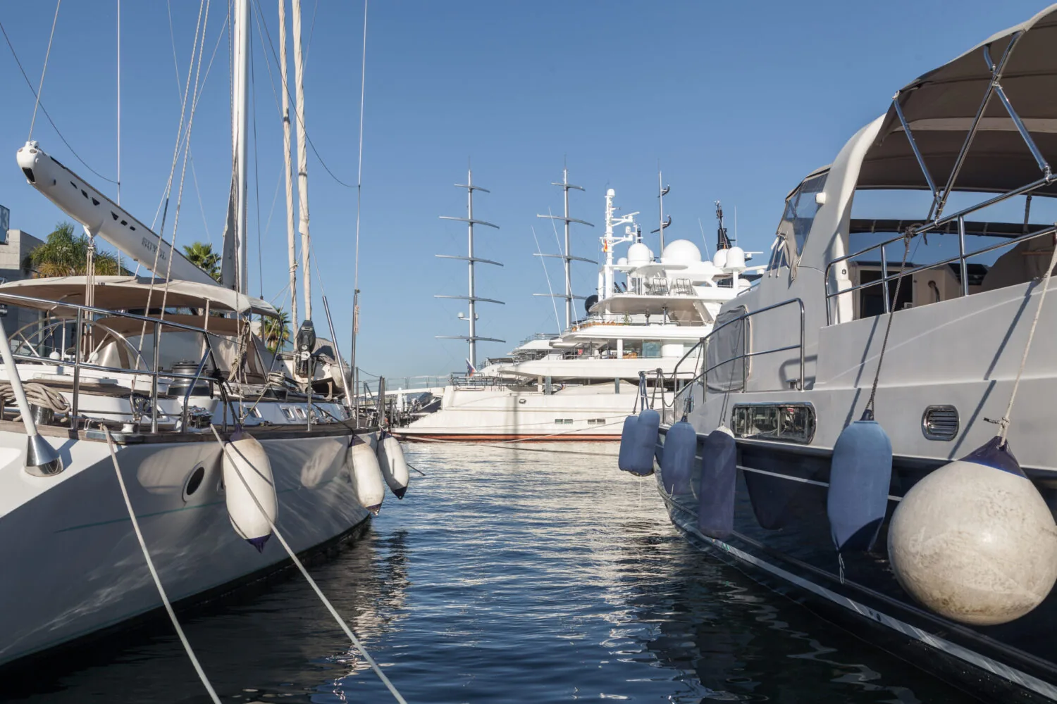 Several luxury yachts moored in a marina on a sunny day.