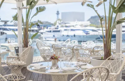 Stylish outdoor dining area at MPVR overlooking a marina with luxury yachts.