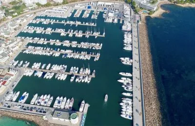 Luftaufnahme des Yachthafens Santa Eulalia mit zahlreichen angedockten Booten und umliegenden Gebäuden am Wasser.