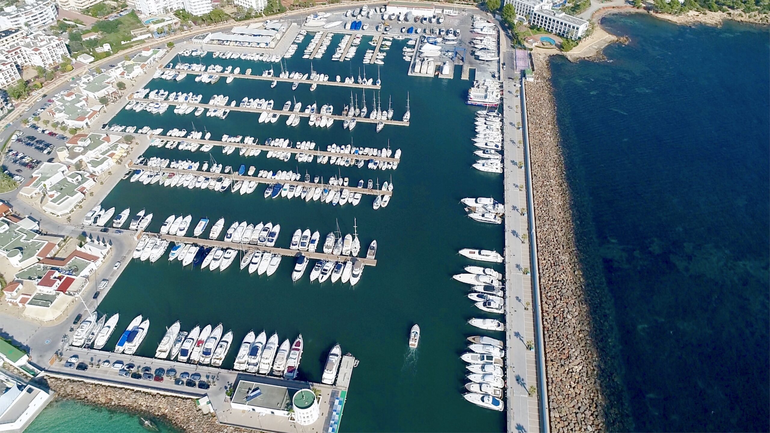 Aerial view of Marina Santa Eulalia with numerous docked boats and surrounding waterfront buildings.