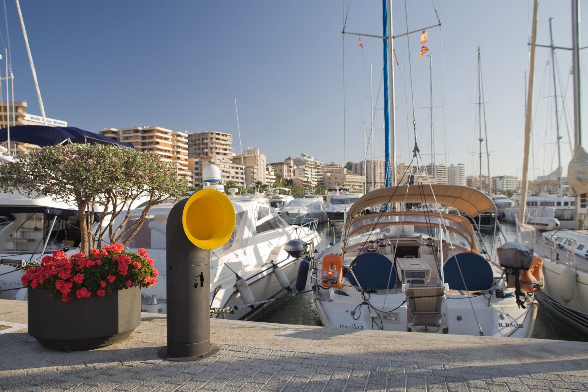 Boats moored in the PDM6 marina with a yellow trash bin and flower planter in the foreground.