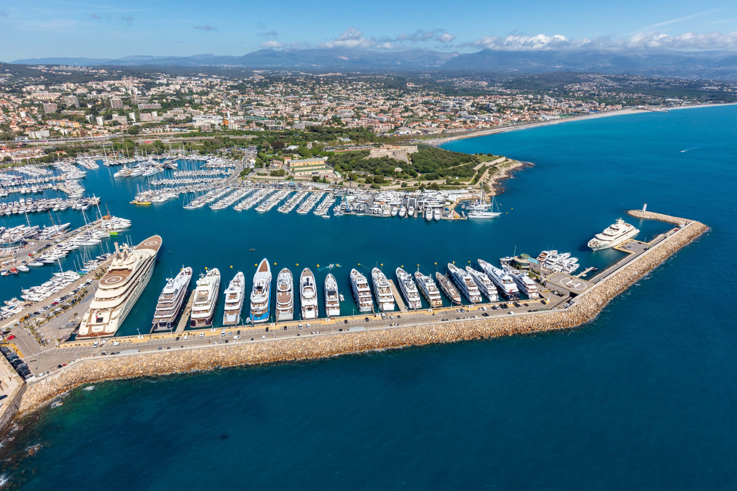 Aerial view of Port Vauban in Antibes, France, showing rows of luxury yachts docked along the harbor and the surrounding coastal cityscape.