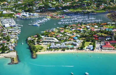 Aerial view of RBM Main marina with yachts, colorful buildings, and a vibrant beachfront.