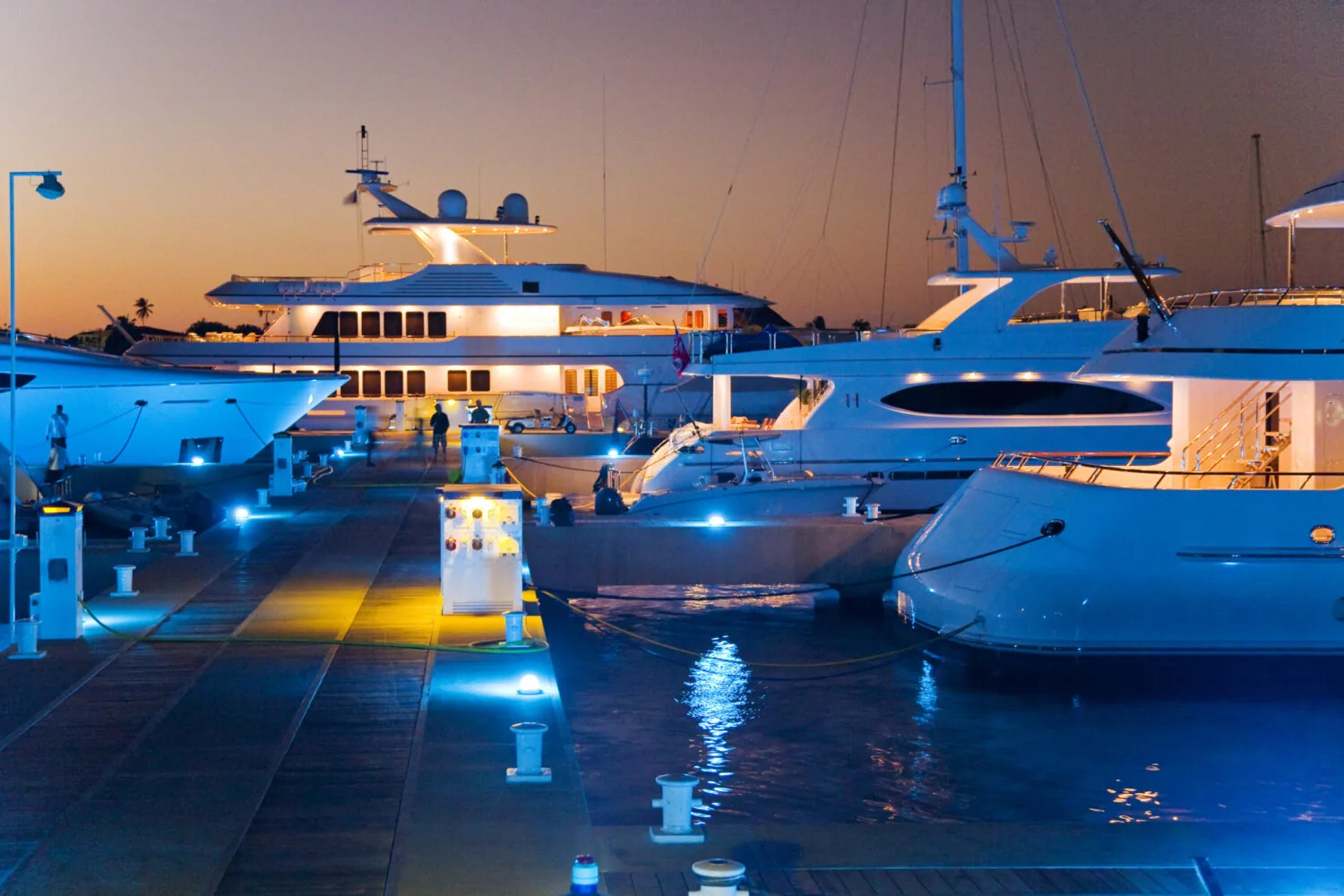 Luxury yachts illuminated by blue marina lights at sunset in RBM Marina.