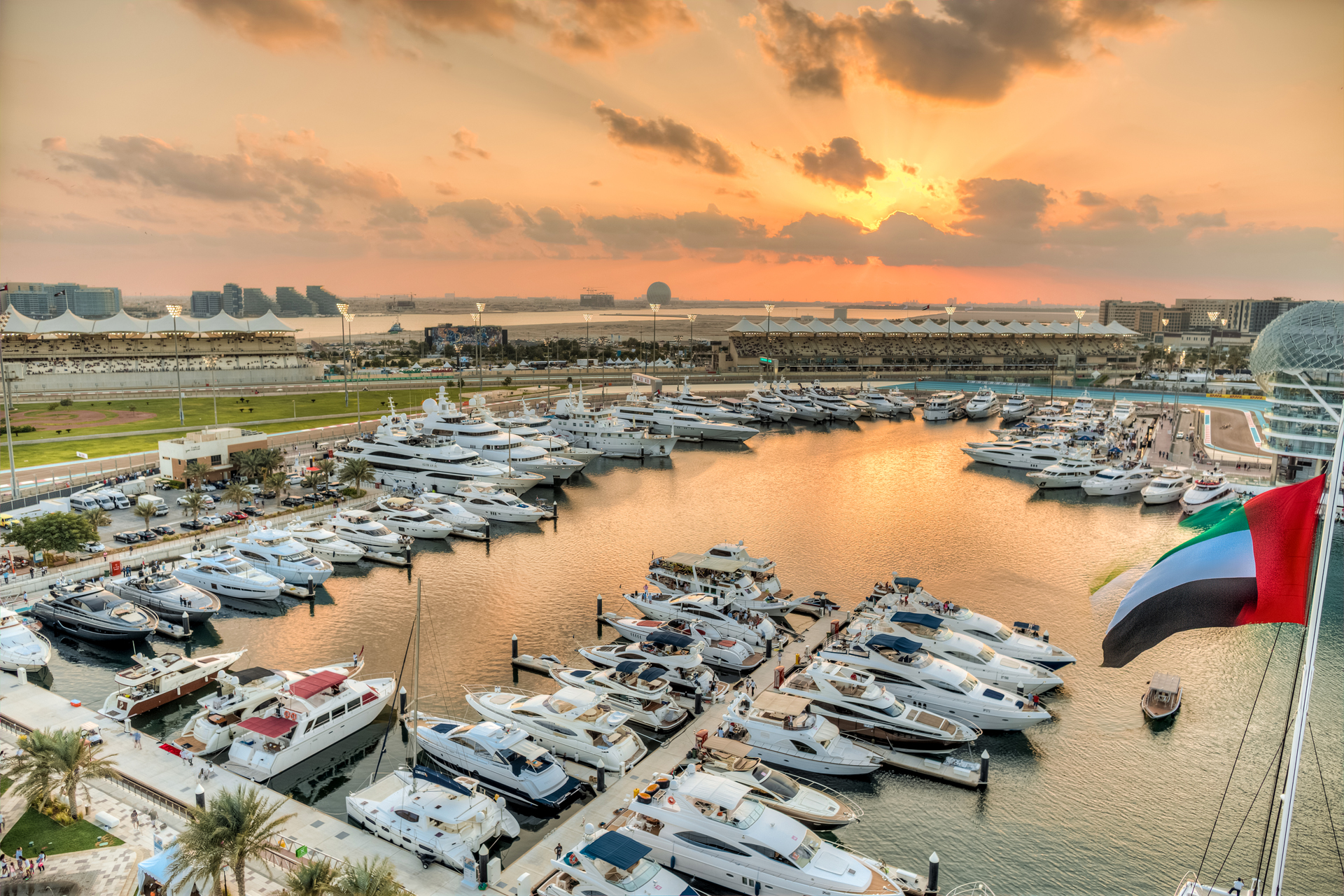 Luxury yachts docked at Yas Marina in Abu Dhabi during a vibrant sunset.