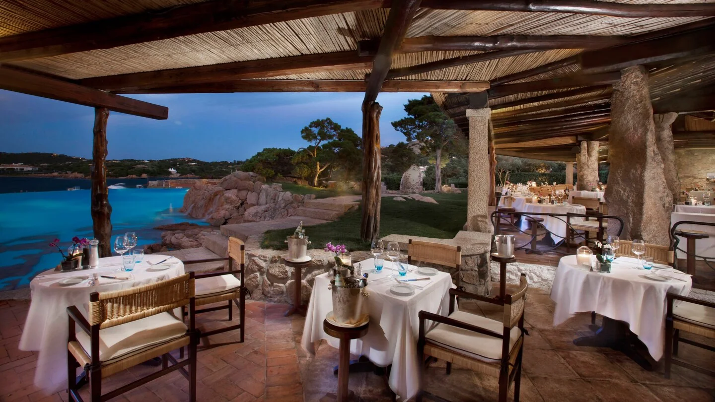 Elegant outdoor dining area at Hotel Pitrizza overlooking the sea in Costa Smeralda at sunset.