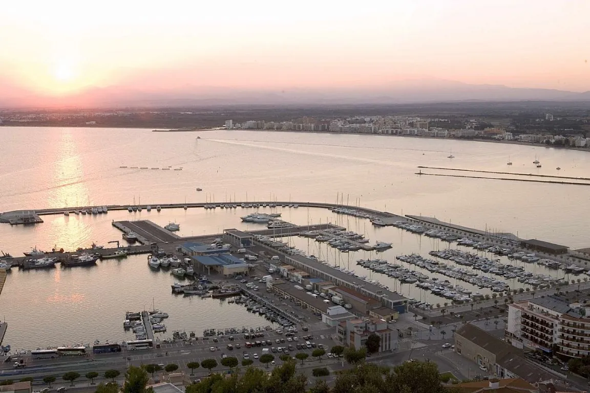 A marina filled with boats and yachts at sunset in the coastal city of Sant Carles de la Ràpita.