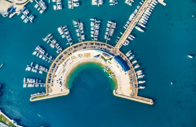 Luftaufnahme des Yachthafens Sukosan in der Nähe von Zadar, Kroatien, die einen halbkreisförmigen Hafen mit zahlreichen vor Anker liegenden Booten und Yachten zeigt.