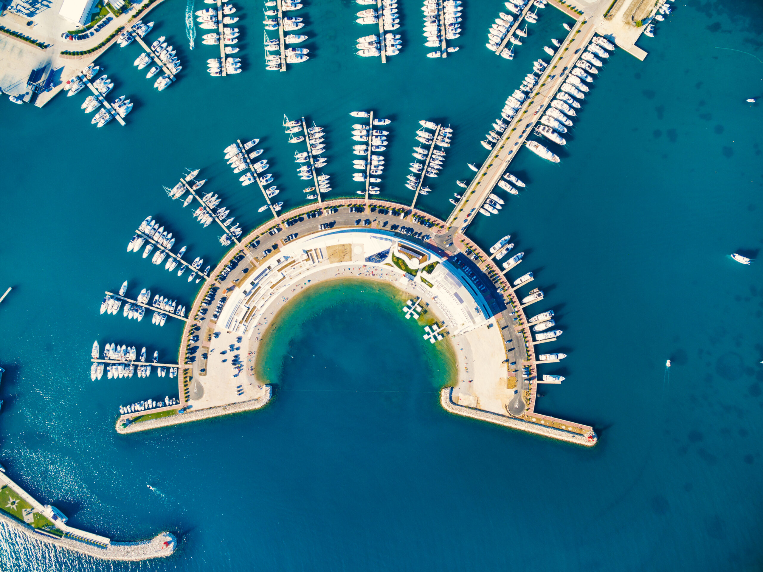 Aerial view of Sukosan marina near Zadar, Croatia, showing a semi-circular harbor filled with docked boats and yachts.