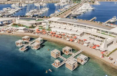 Luftaufnahme des Portus Beach Clubs im D-Marin Dalmacija mit schwimmenden Cabanas, Sonnenliegen und einem Yachthafen voller Yachten.