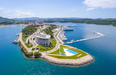 Luftaufnahme des Yachthafens D-Marin Mandalina mit Luxusyachten, modernen Gebäuden und einem Schwimmbad auf einer malerischen Halbinsel.
