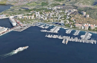 Luftaufnahme eines belebten Yachthafens mit zahlreichen Yachten und Kreuzfahrtschiffen, die in der Nähe einer Küstenstadt angedockt sind.