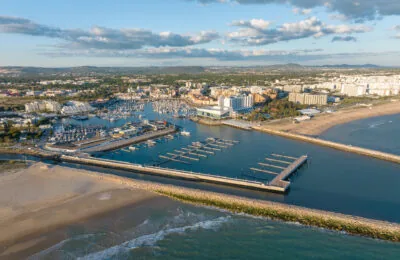 Aerial view of Vilamoura Marina with surrounding buildings, beach, and ocean in the Algarve region, Portugal.