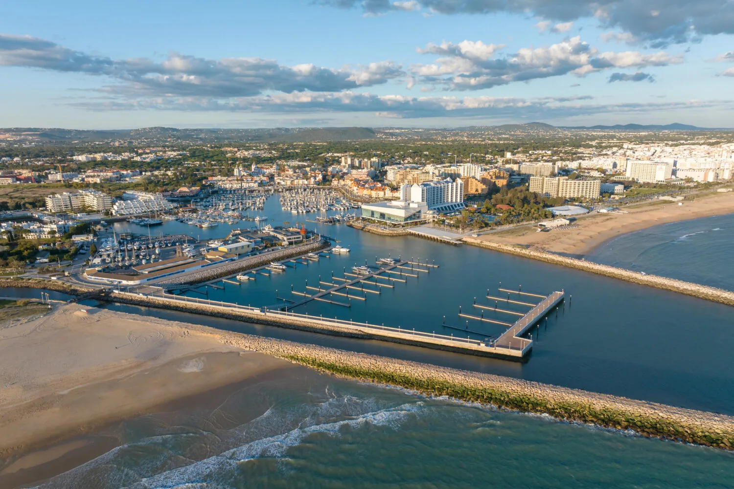 Aerial view of Vilamoura Marina with surrounding buildings, beach, and ocean in the Algarve region, Portugal.