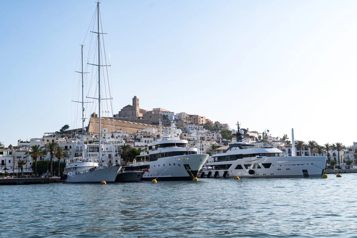 In einem Yachthafen vor Anker liegende Yachten, im Hintergrund sind die Altstadt von Ibiza und ihre Kathedrale zu sehen.